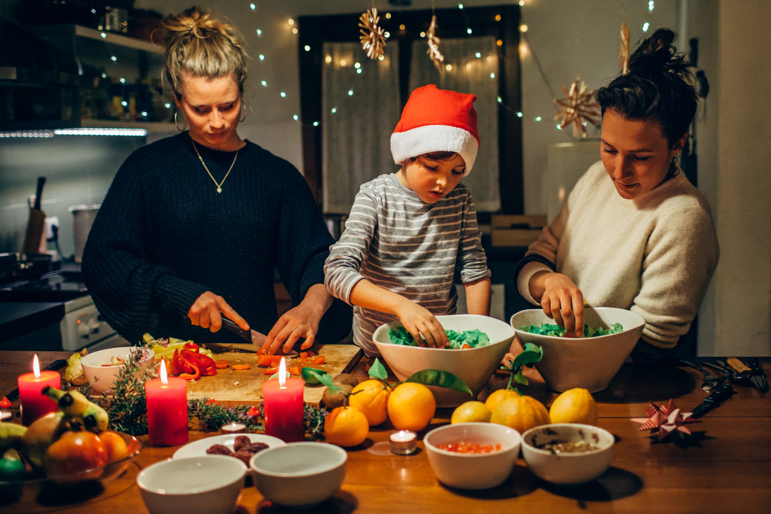 Tips för en hållbar jul. En familj med ett barn i tomtemössa lagar julmat.