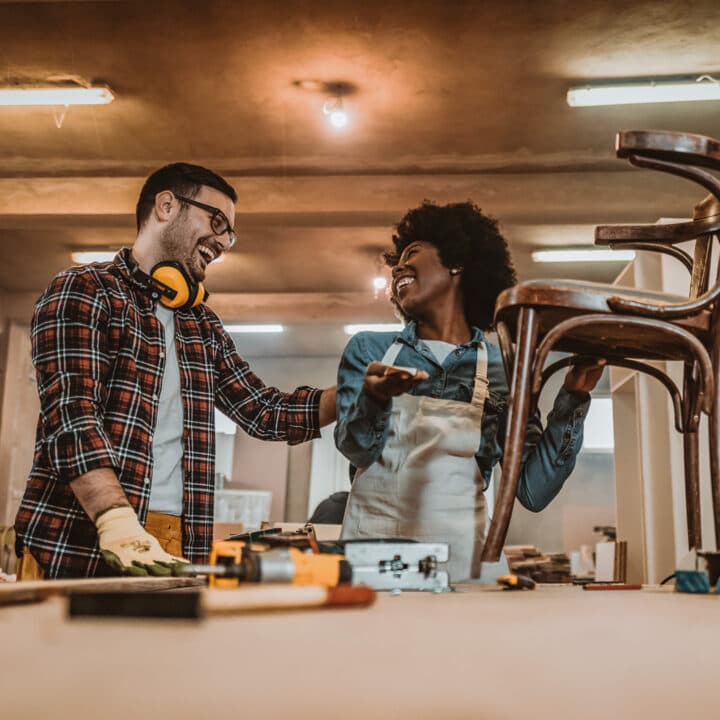 Till miljöpolicysidorna. One African-American Woman and African-American man carpenters using tools ...
