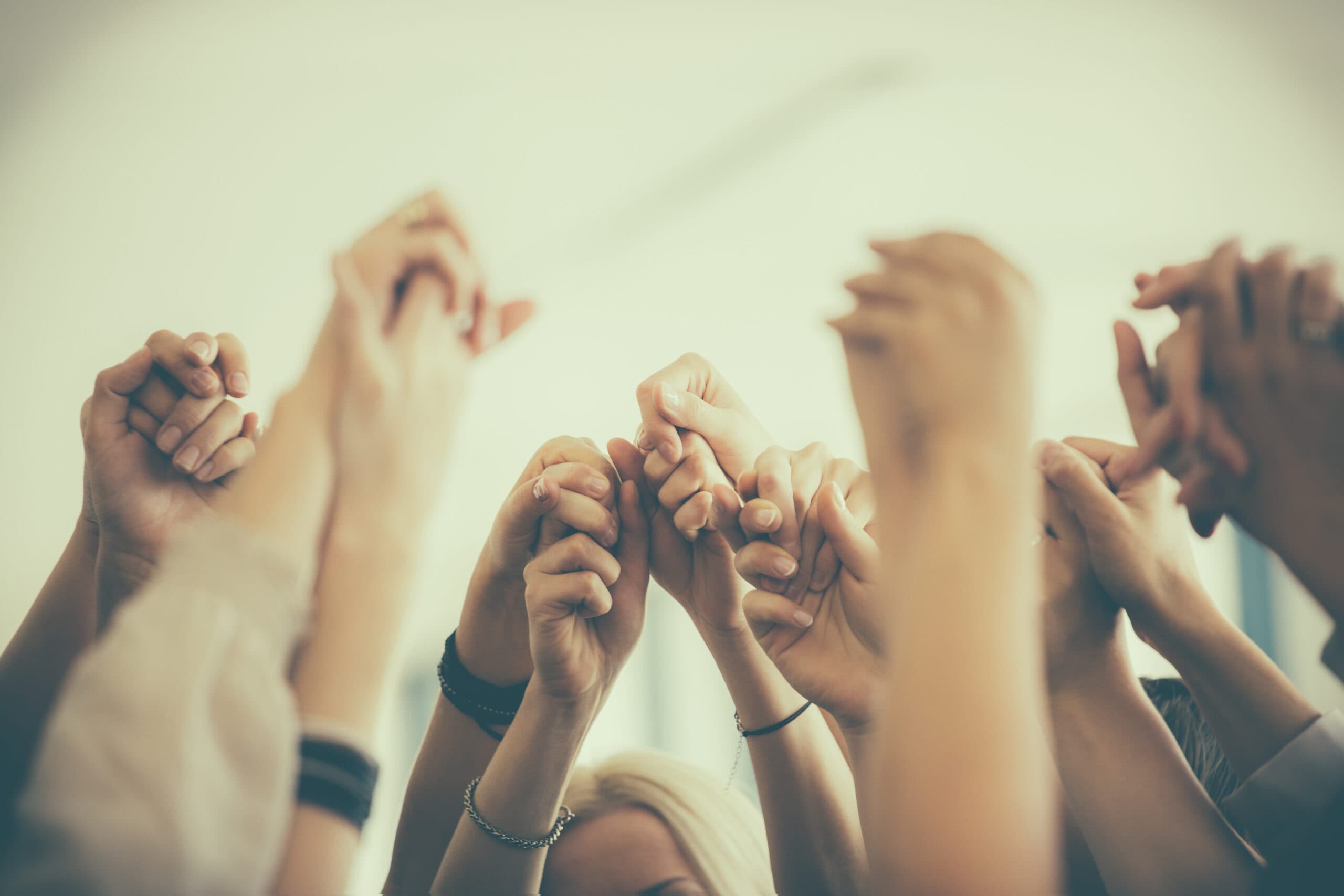 Group of women standing toghether in the circle and holding raised hands. Close up of hands. Unrecognizable people.