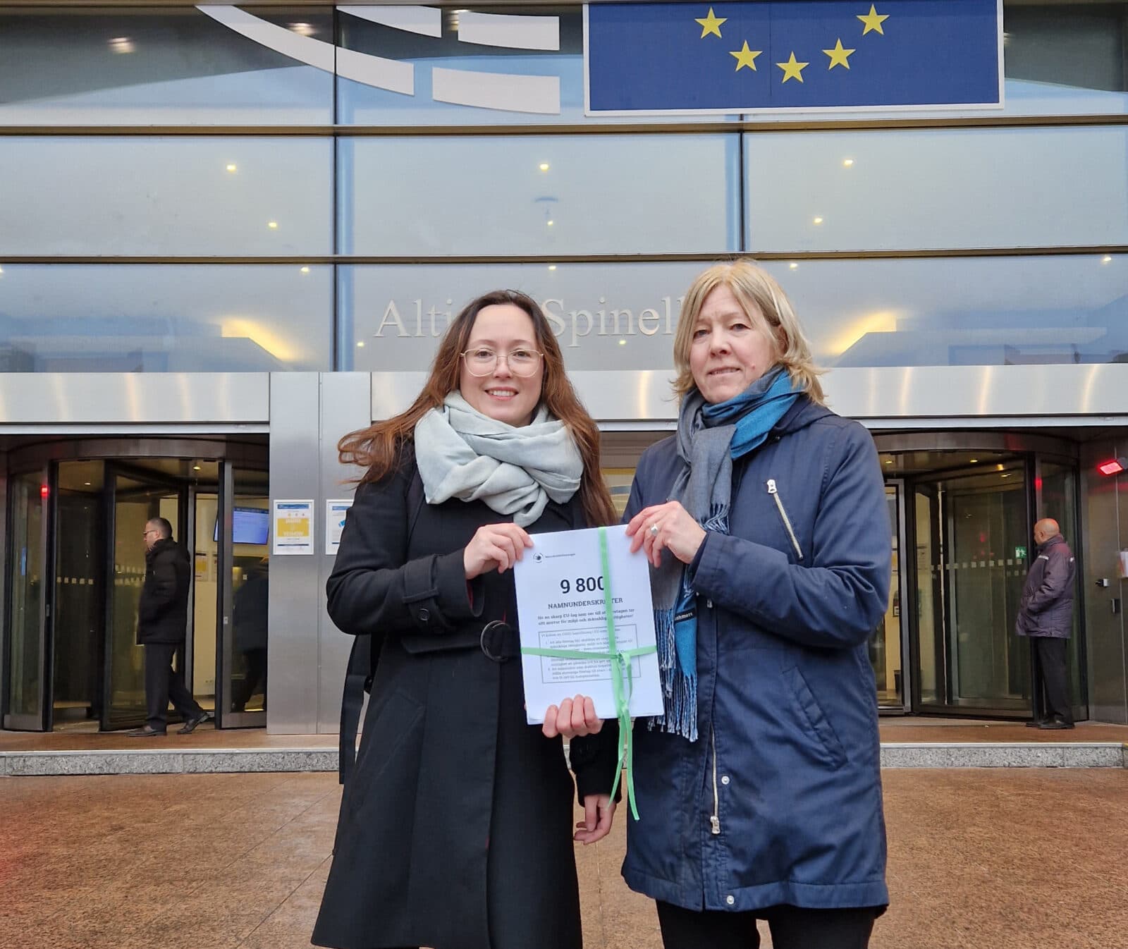 Sofia Tapper och Marja Wolpher framför EU-parlamentet i Bryssel med namninsamlingen för miljöförsvarare.