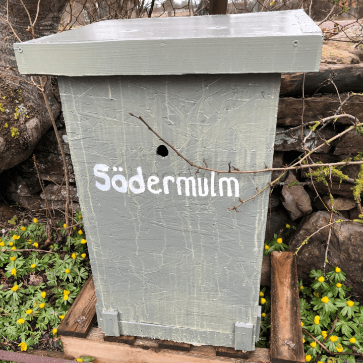 Bilden visar en grå trälåda med ett tak och en rund öppning på framsidan, som ser ut att vara en ...